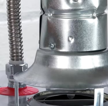 Close-up of a gas water heater draft hood and flexible stainless steel water connector.
