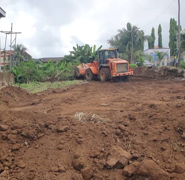 An orange front-end loader leveling soil at a residential construction site for land clearing.