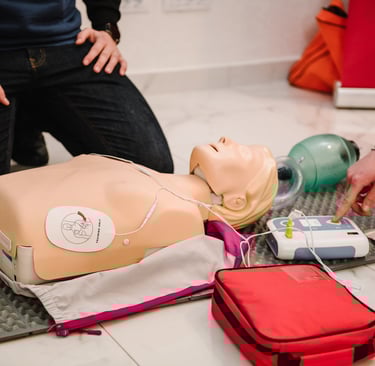 Close up image of CPR mannequin with an AED trainer next to it