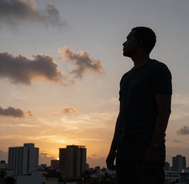 A moody, low-angle shot of a film director's silhouette standing against a sunset over the city of Luanda, Angolana architecture in the background, slate grey clouds and antique gold horizon lines.