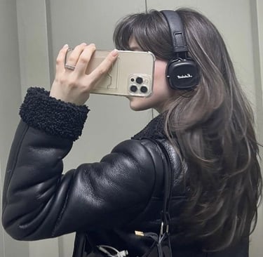Woman with long brown hair taking mirror selfie wearing black leather puffer jacket