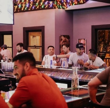 A group of friends socializing at a busy sports bar with neon lights and TV screens.