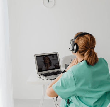 a woman in a green robe is sitting at a desk with a laptop computer