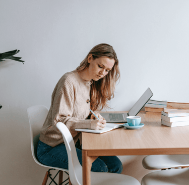 a woman sitting at a table with a laptop and a laptop