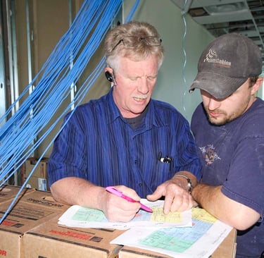 Technicians review a cabling project design plan at a professional network installation site.