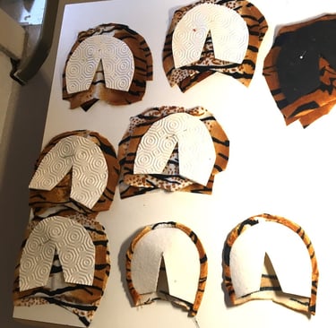 Tiger print fabric pattern pieces with white stabilizers laid out for a sewing project.