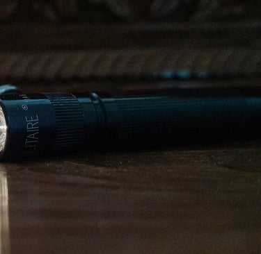  lanterna compacta EDC acesa sobre mesa com itens de everyday carry