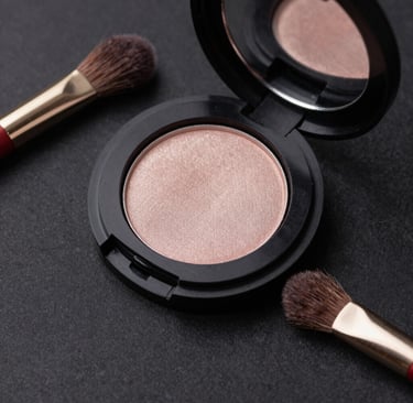 An elegant compact of shimmering gold eyeshadow with a rich black case, placed on a glossy surface.