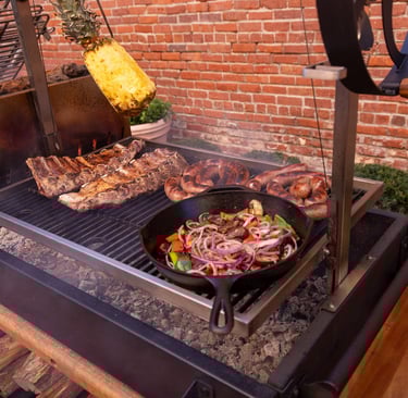a variety of meats and vegetables cooking on a santa maria grill