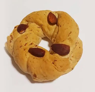 Golden brown Italian taralli pastry with whole almonds on a white background.