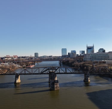 Panoramic aerial view of the Nashville, TN skyline and Cumberland River, featuring the Shelby Street