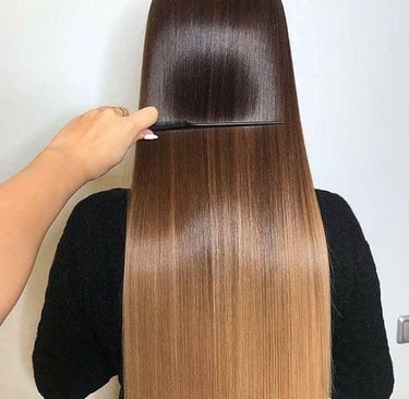 Estilista peinando cabello largo, lacio y brillante con un degradado balayage de castaño a rubio.