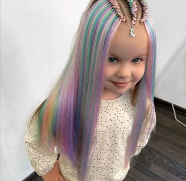 Niña con extensiones de cabello arcoíris y peinado trenzado infantil.