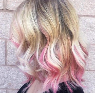 Cabello rubio ondulado a la altura de los hombros con balayage rosa vibrante y mechones en tonos pas