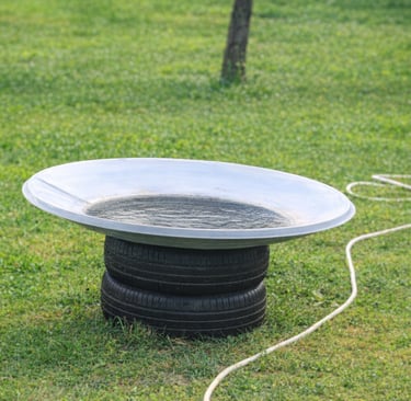 DIY garden fountain made from two stacked car tyres and a repurposed satellite dish filled with wate