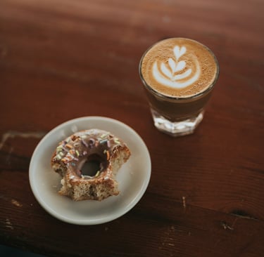 a cup of coffee and a doughnut on a table