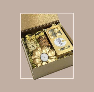 Golden box for festive gifting with Ferrero Rocher, dry fruits, and a t-light holder.