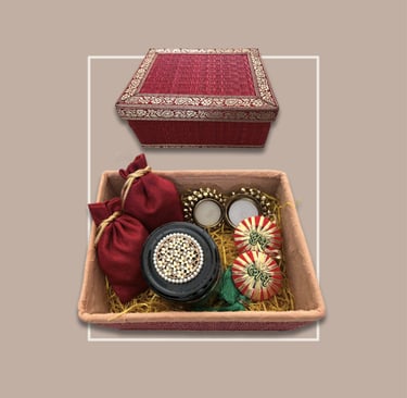 Traditional red textured festive gifting hamper with gold embroidery and diyas.