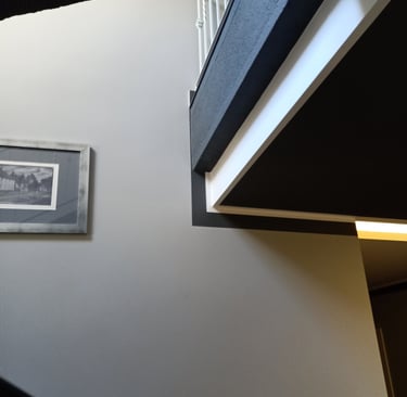 Modern minimalist staircase interior featuring geometric wall angles and a framed black and white picture.