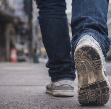 Persona caminando por la ciudad con tenis de uso diario mostrando desgaste en la suela