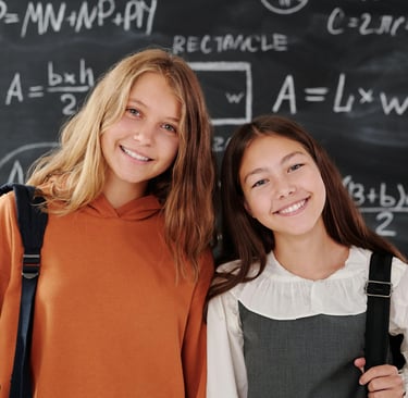 Smiling GCSE Maths students standing in front of their GCSE Maths tutors black board