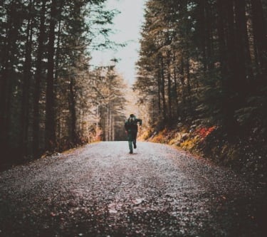 a person walking down a road with a person holding a camera