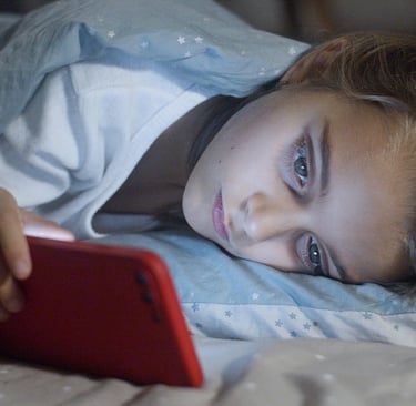 a child is laying on a bed with a red phone