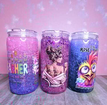 Three custom glitter snow globe tumblers with teacher, empowerment, and rooster designs.
