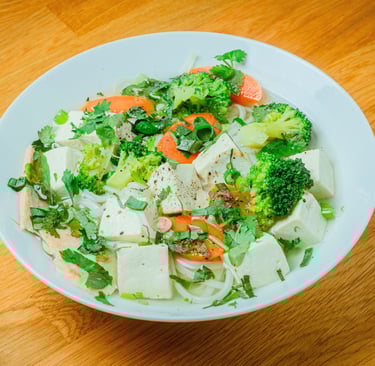 Bowl of Vietnamese noodle soup with sliced beef, bean sprouts, herbs, and lime on a wooden table