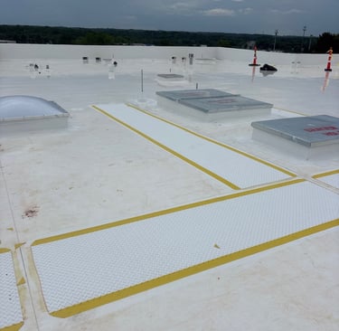 Wide-angle view of a clean commercial TPO roof system with designated yellow-bordered walkway pads, 