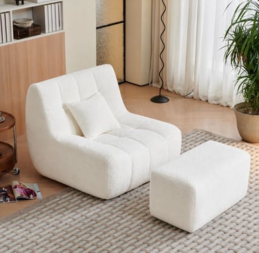 Modern white boucle accent chair with matching ottoman on a textured rug in a cozy living room.