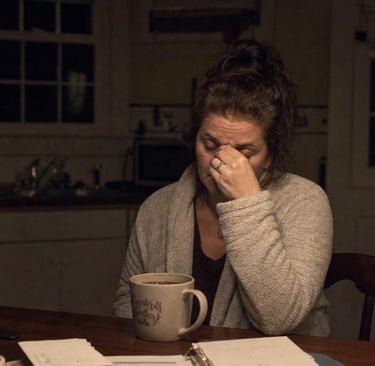 Exhausted family caregiver showing warning signs of caregiver burnout late at night in the kitchen