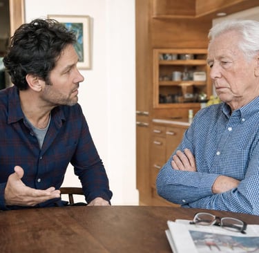 Adult son having a calm, caring conversation with his resistant senior father who refuses help