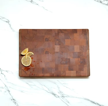 Overhead view of an end-grain chopping board styled with lemon slices and water droplets