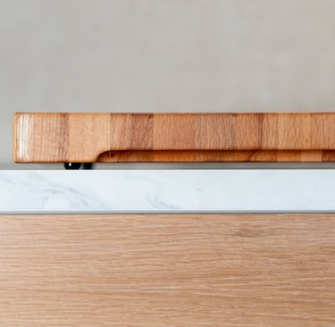 Side view of a thick wooden chopping board resting on a marble worktop