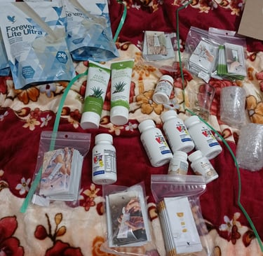 A collection of Forever Living health and beauty products, including Aloe Jojoba shampoo and Lite Ultra protein powder.