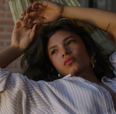 Una joven pensativa con una camisa abierta relajándose en una hamaca tejida al aire libre