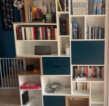 a bookcase with a television and a laptop on the floor