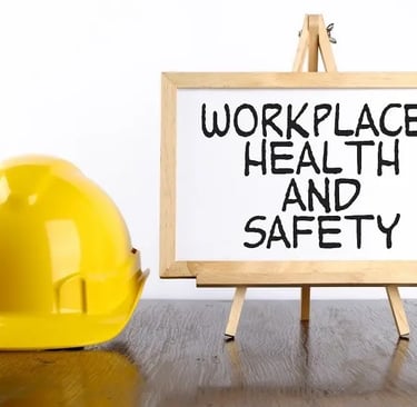 Yellow hard hat next to a sign that says Workplace Health and Safety on a wooden desk.