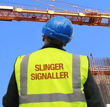 A slinger signaller in a high-visibility vest and blue hard hat monitoring a construction crane.