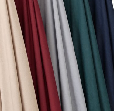 Close-up of delicate embroidery on a soft beige hijab draped over a wooden chair.