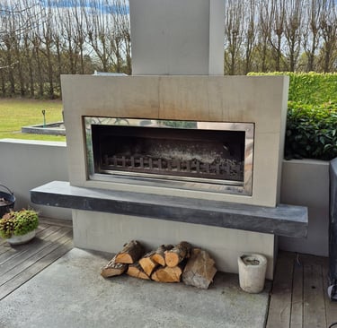 Modern outdoor fireplace with a concrete mantel and wood logs on a patio deck.