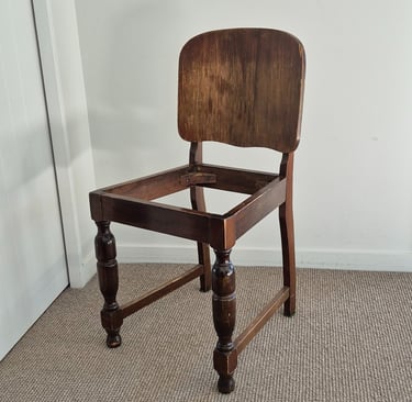 Vintage dark wood dining chair frame without a seat cushion, featuring turned legs and a solid backrest.