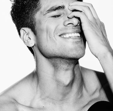 Black and white portrait of a smiling Dany Peña with curly hair and hand on his face.