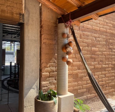 Rustic brick distillery interior with terracotta gourds hanging from a wooden beam.