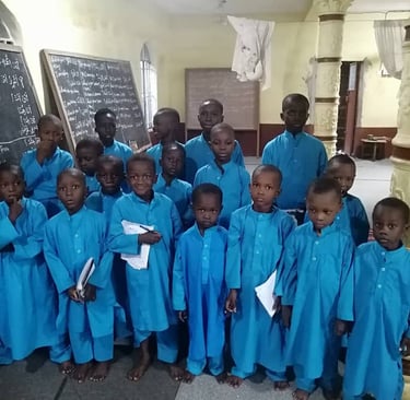 Smiling child holds Mushaf while studying Islam at Maakitheena school.