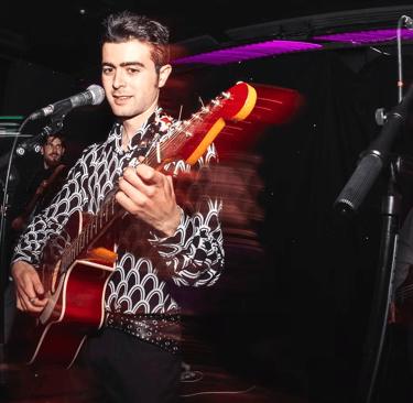 Brighton UK singer songwriter Olly Williams playing electric guitar during live show