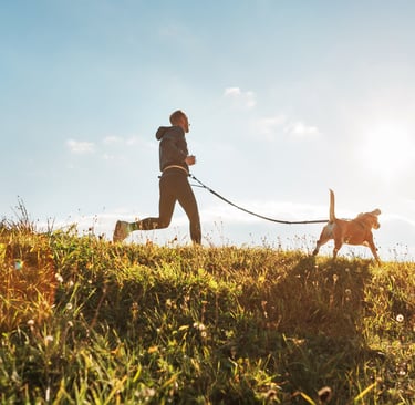 Hombre corriendo con su perro en una colina