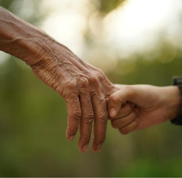 Mano de adulto mayor sosteniendo la mano de alguien más joven
