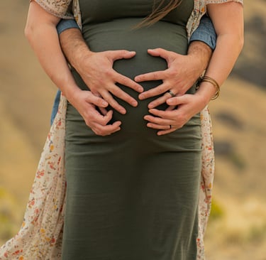 Mujer embarazada acariciando su vientre mientras su pareja la abraza